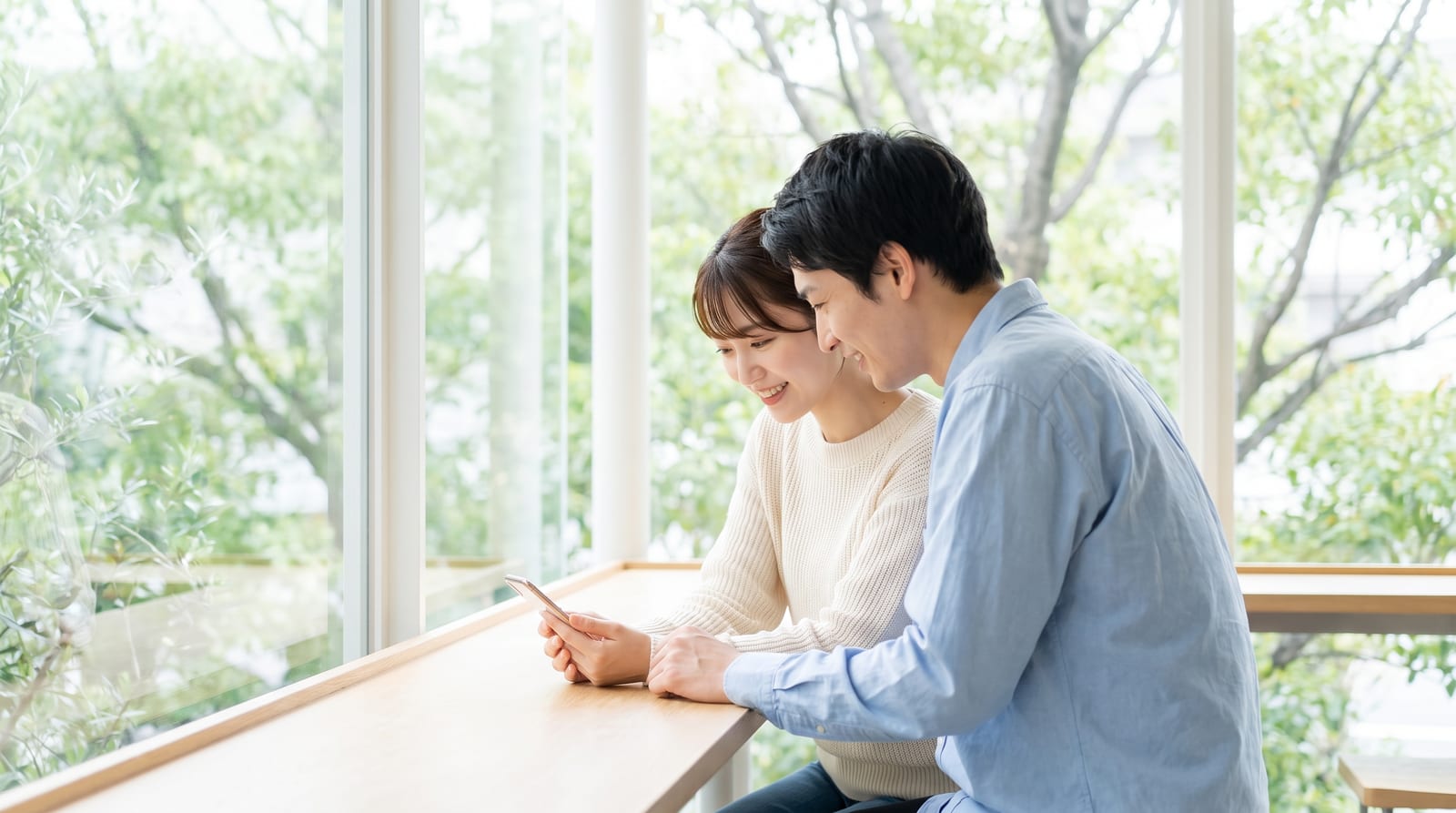 カフェのテーブルでスマートフォンの送金画面を確認しているところ