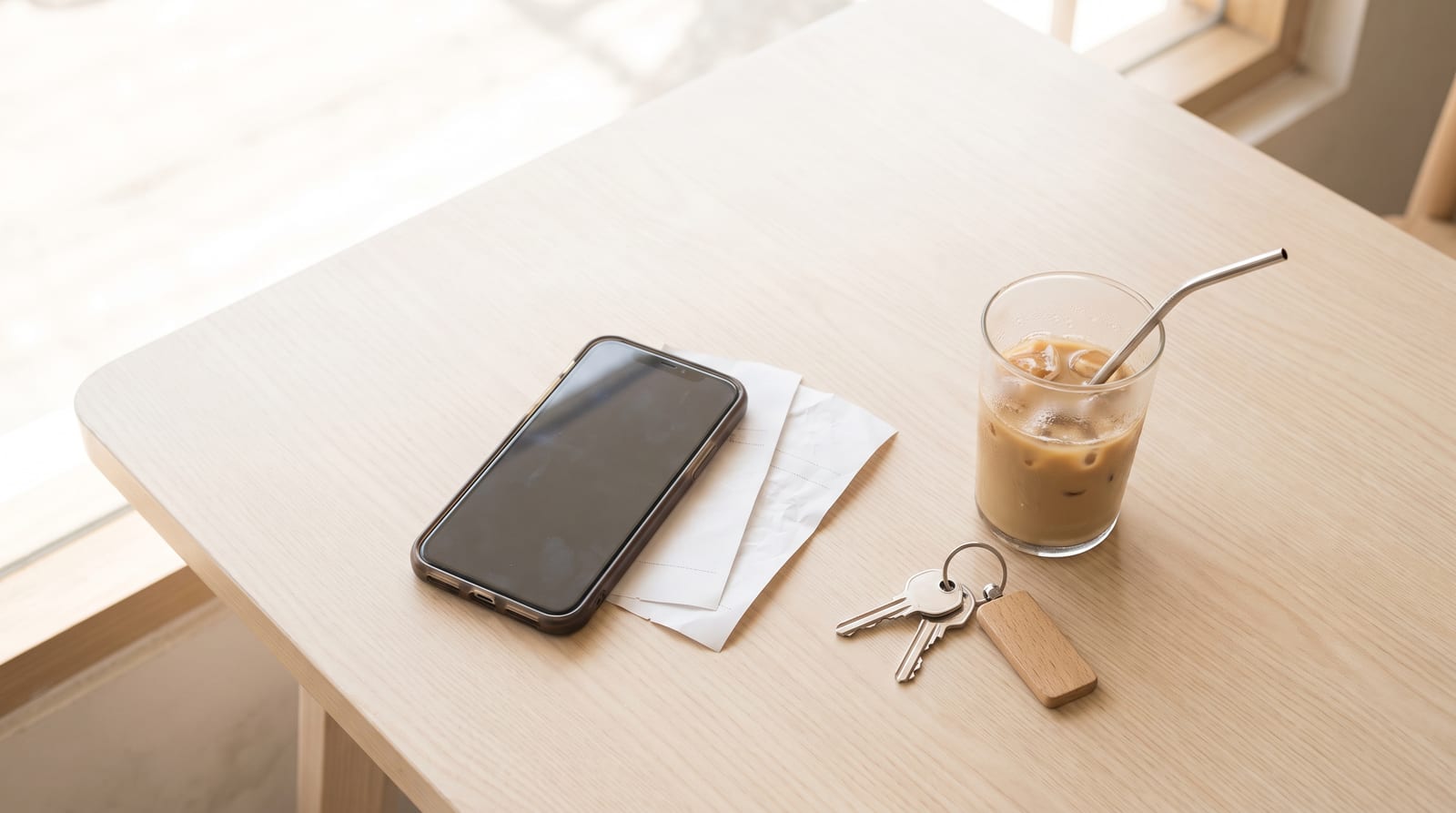 明るいカフェのテーブルに置かれたスマートフォンとレシート